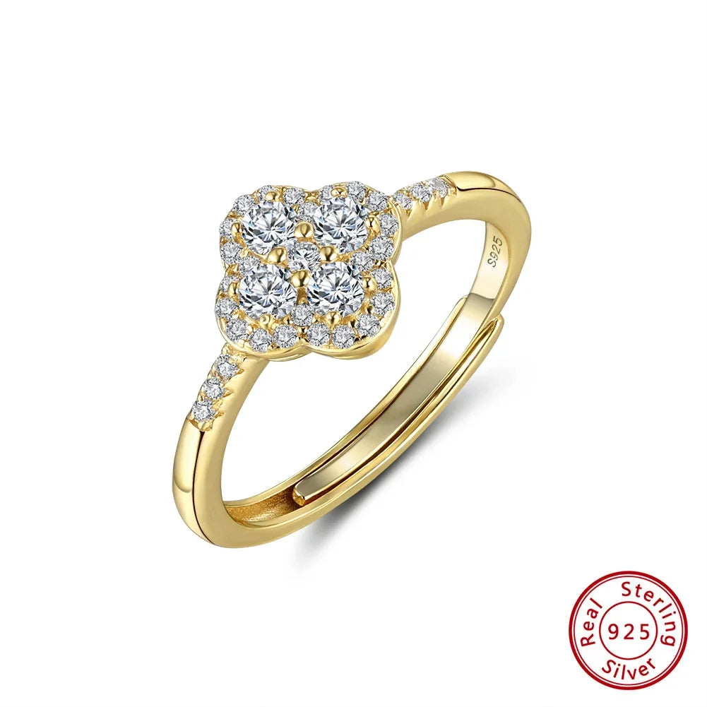 Einstellbarer Ring aus vergoldetem 925er Silber mit vierblättrigem Kleeblatt-Motiv, besetzt mit funkelnden Zirkonia-Steinen. Die Ringschiene ist teilweise ebenfalls mit kleinen Zirkonia besetzt. Am unteren Rand ist das 'Real 925 Sterling Silver' Echtheitssiegel sichtbar.