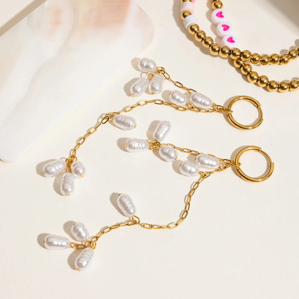 Ein Paar lange Ohrhänger mit Acrylperlen aus 18K vergoldetem Edelstahl, neben einer goldenen Halskette liegend.