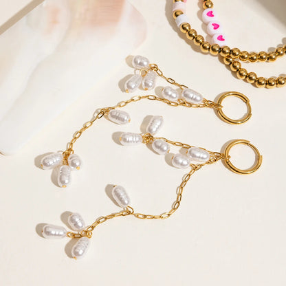 Ein Paar lange Ohrhänger mit Acrylperlen aus 18K vergoldetem Edelstahl, neben einer goldenen Halskette liegend.