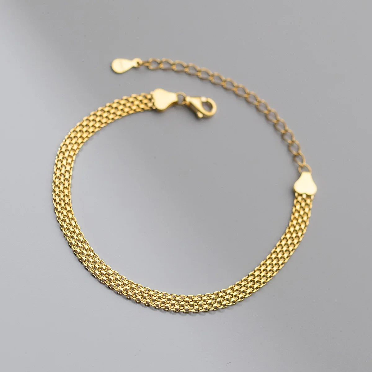 Detailansicht des stabilen Karabinerverschlusses und der Verlängerungskette mit Herz-Endkappe am goldenen Mesh-Armband