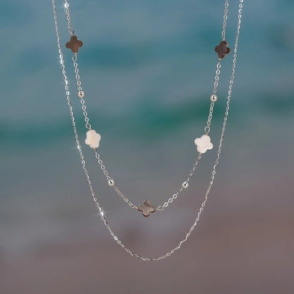 Zarte, doppelte Halskette aus 925er Silber mit Kleeblättern, am Strand oder Meer.