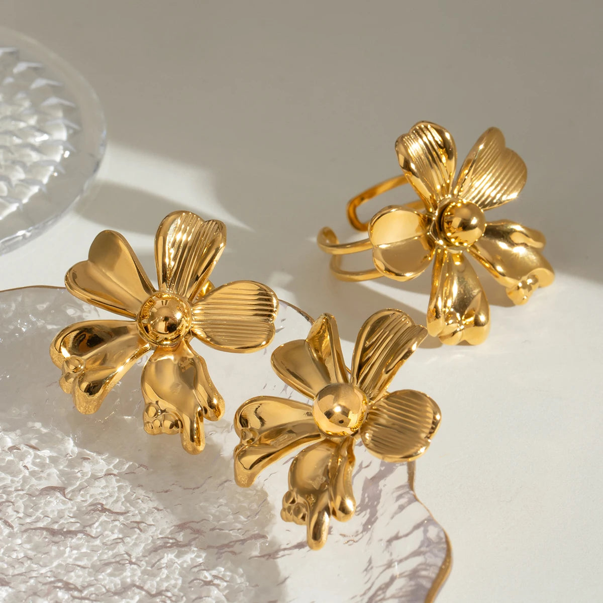 Elegantes Stillleben-Foto des gewellten, vergoldeten Edelstahlrings, platziert neben dem Fuß eines Kristallglases, um die glänzende Oberfläche hervorzuheben.