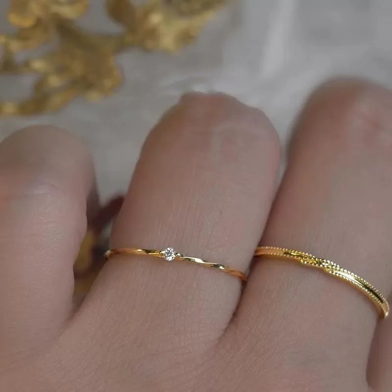 Zwei 18K Gold Platin vergoldete 925 Silber Ringe mit einzelnen Zirkonia-Steinen, übereinander am Finger getragen (Stapellook).