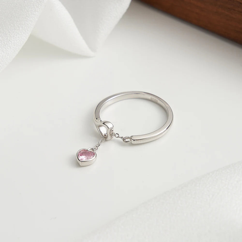 Silberner Ring aus 925er Sterling Silber mit zartem rosa Zirkonia-Herzanhänger auf weißem Hintergrund.