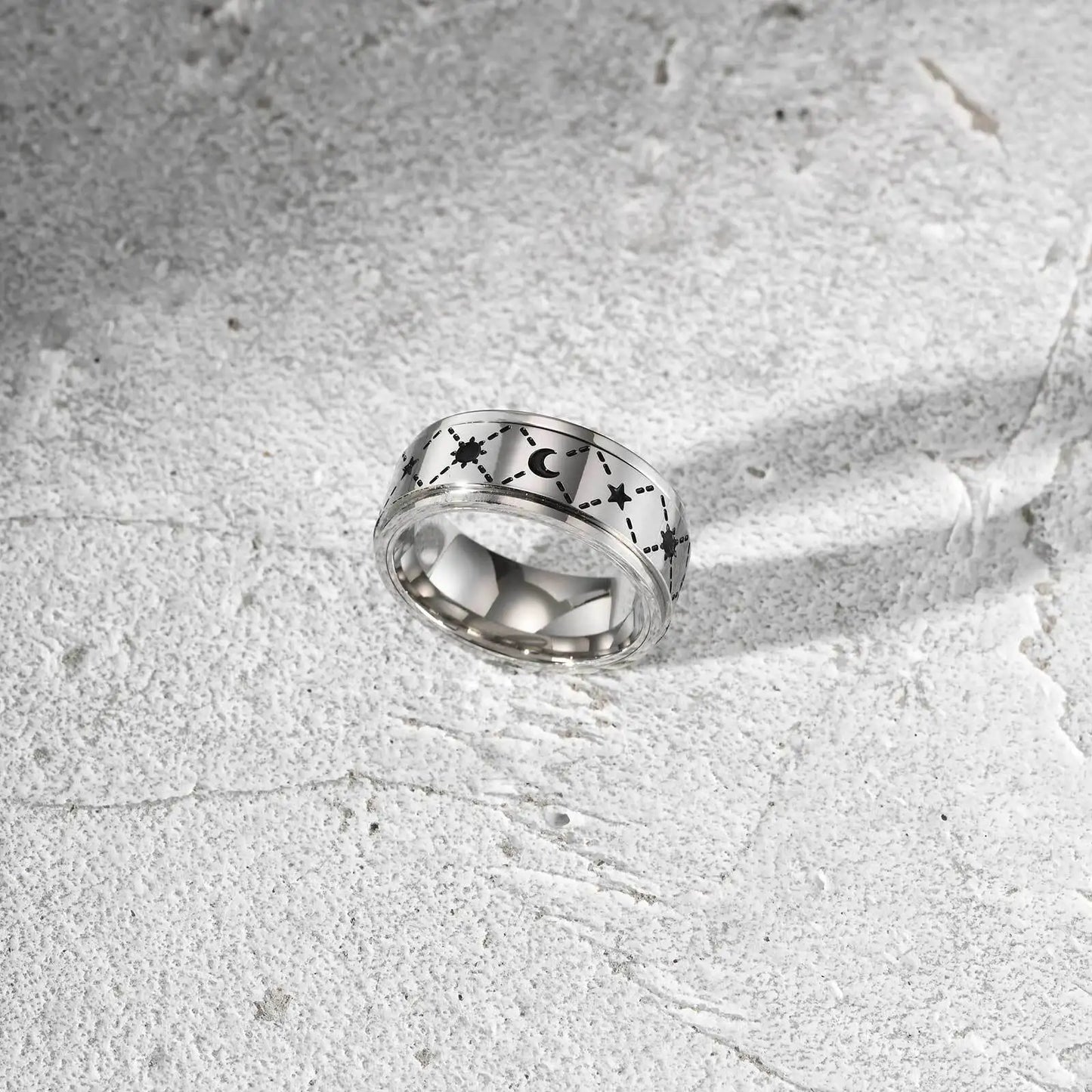 Freigestellter, silberfarbener Edelstahl-Spinner-Ring mit Sternen-Muster (andere Perspektive).