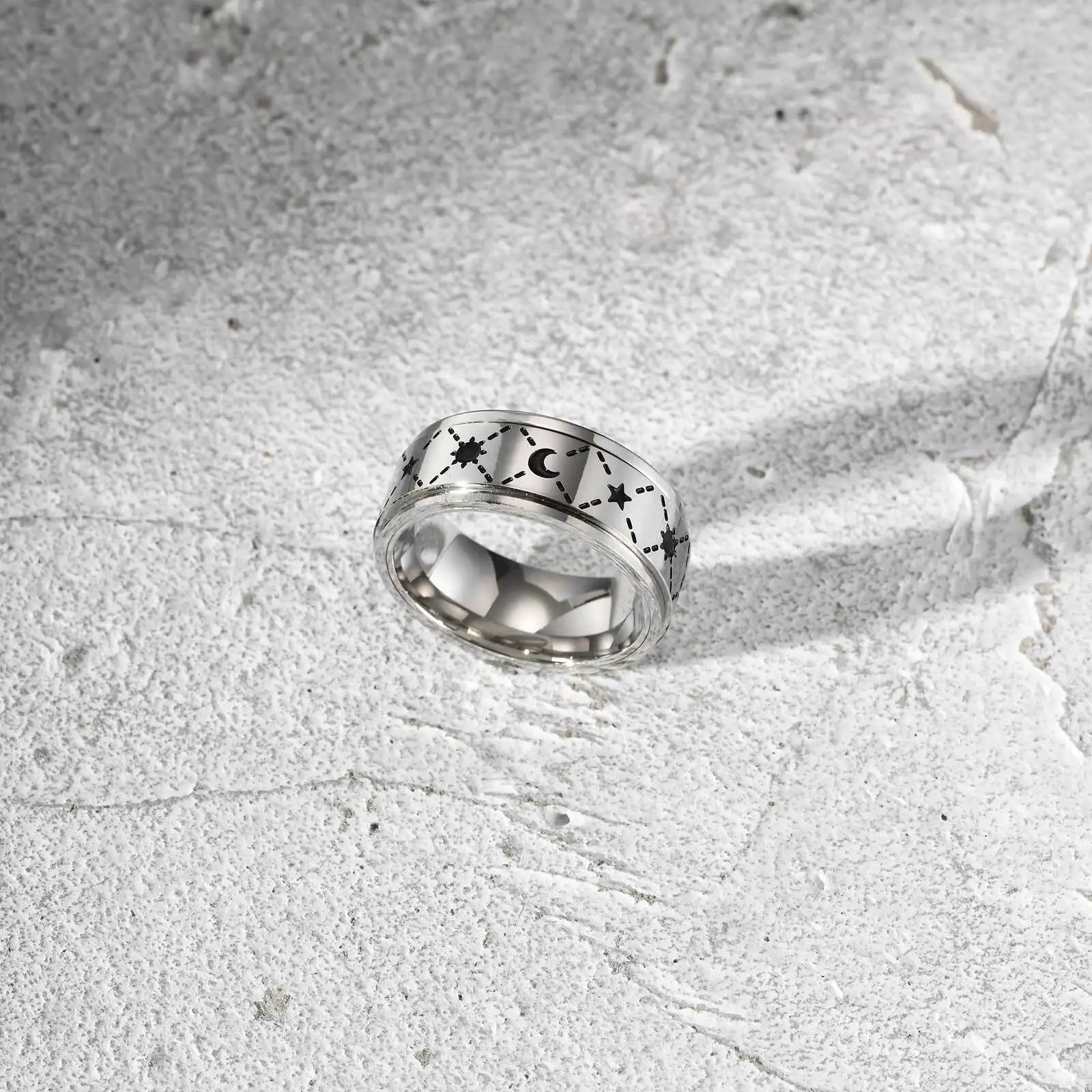 Freigestellter, silberfarbener Edelstahl-Spinner-Ring mit Sternen-Muster (andere Perspektive).