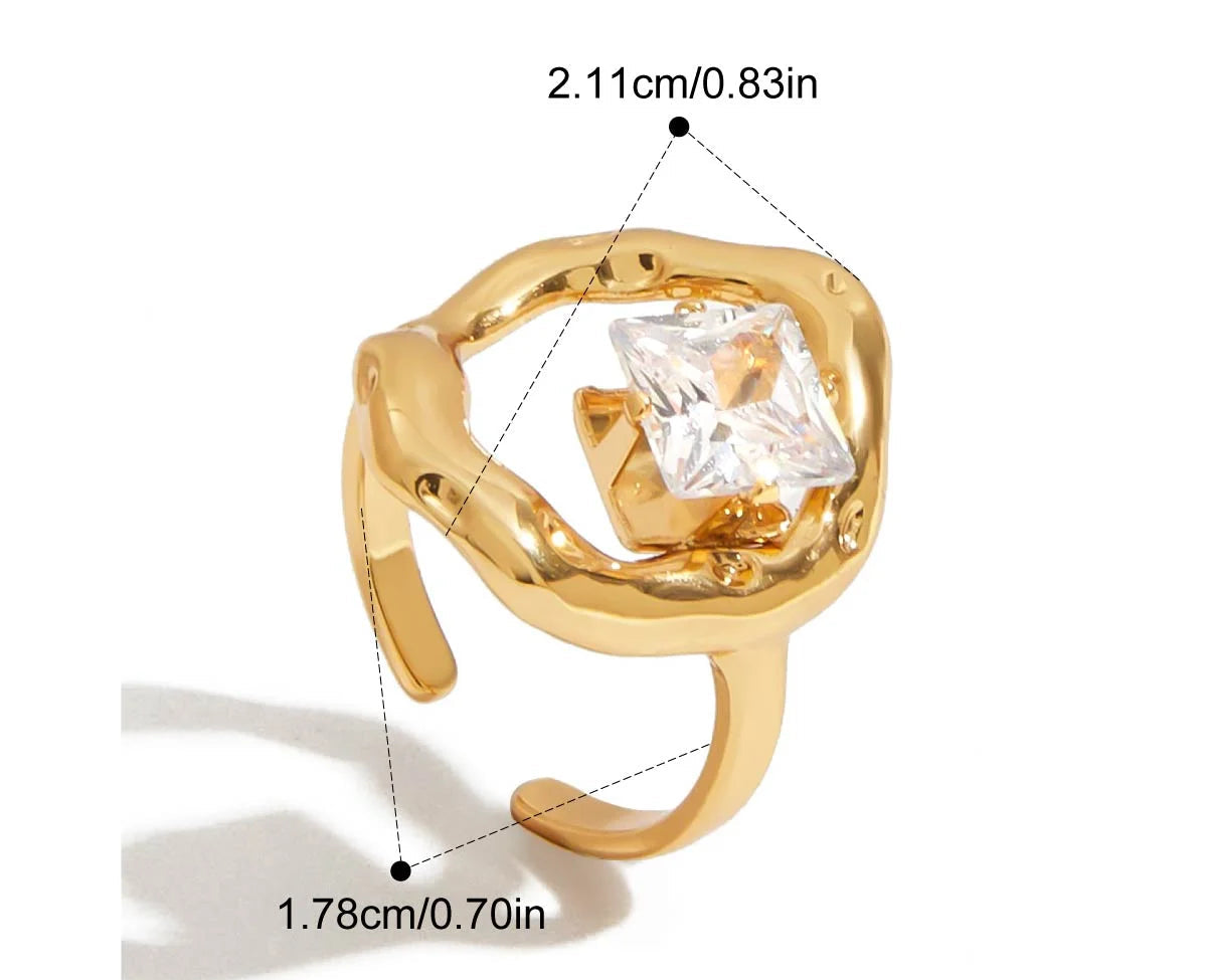 Grafische Darstellung eines goldenen Rings mit 18K PVD-Vergoldung. Er hat eine geschwungene, fließende Form und ist mit einem großen, klaren Zirkonia Stein besetzt. Die Maße sind ebenfalls angegeben mit einem Innendurchmesser von 1,8 cm und einer Breite von 2,10 cm.