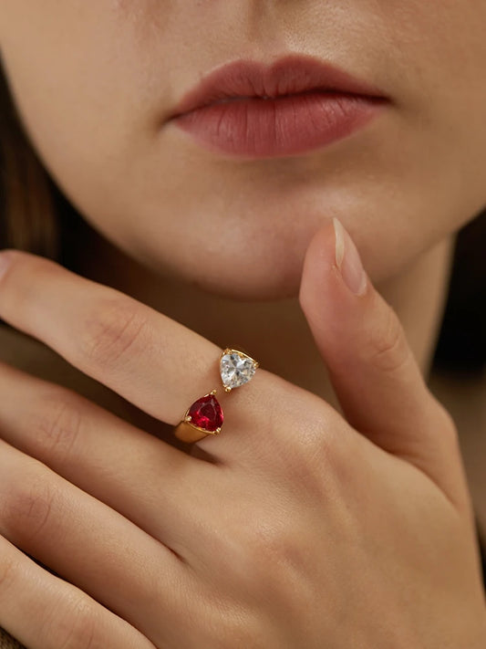 18K vergoldeter Offener Ring mit rotem und klarem Zirkonia-Herzstein, getragen an weiblicher Hand, Detailaufnahme