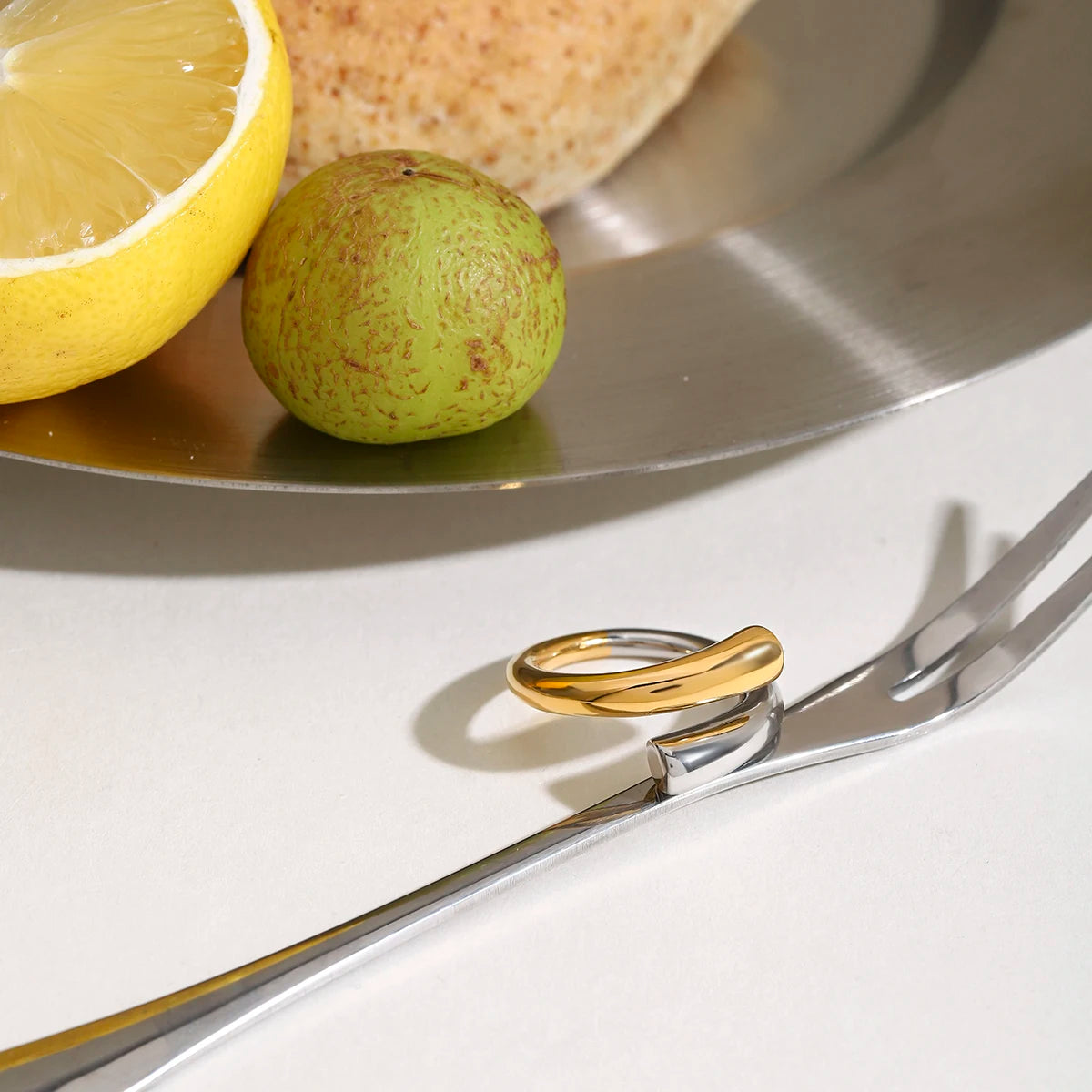 Bicolor-Ring in Gold und Silber auf Besteck platziert | Ring aus PVD 18K vergoldetem Edelstahl für besondere Anlässe