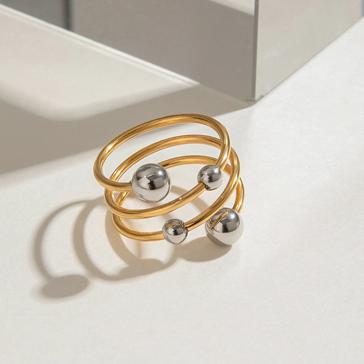 „Dreireihiger Statement-Ring in Bi-Color Optik: PVD-vergoldeter Edelstahl kombiniert mit polierten silbernen Kugelelementen.“
