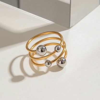 „Dreireihiger Statement-Ring in Bi-Color Optik: PVD-vergoldeter Edelstahl kombiniert mit polierten silbernen Kugelelementen.“