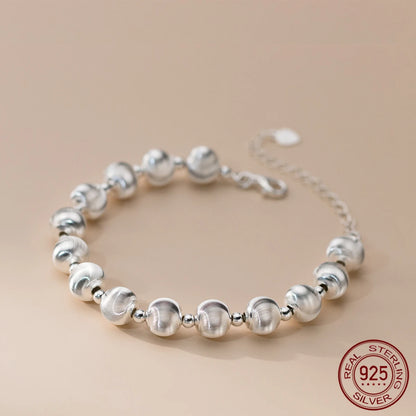 Nahaufnahme eines glänzenden Armbandes aus 925er Sterling Silber, bestehend aus mattierten und glänzenden Kugelperlen, mit einem verstellbaren Kettenverschluss. Ein "925 STERLING SILVER" Siegel ist sichtbar.