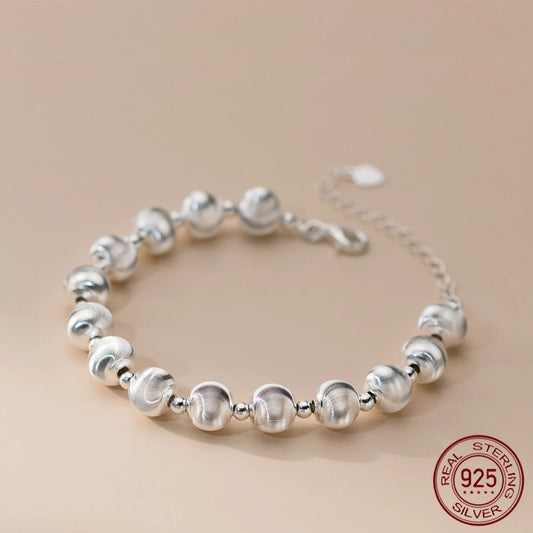 Nahaufnahme eines glänzenden Armbandes aus 925er Sterling Silber, bestehend aus mattierten und glänzenden Kugelperlen, mit einem verstellbaren Kettenverschluss. Ein "925 STERLING SILVER" Siegel ist sichtbar.
