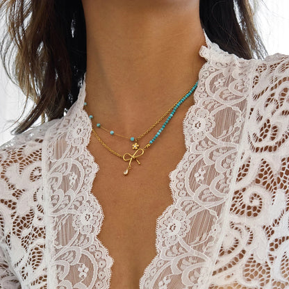 Goldene Halskette aus Edelstahl mit 18K PVD Vergoldung, türkisfarbenen Perlen und Schleifen-Anhänger