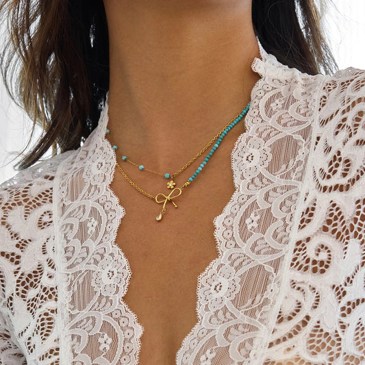 Goldene Halskette aus Edelstahl mit 18K PVD Vergoldung, türkisfarbenen Perlen und Schleifen-Anhänger