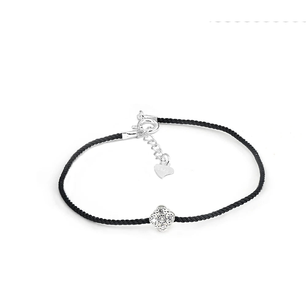 Armband mit schwarzem Textilband, das einen kleinen runden Anhänger aus 925er Silber mit einem zentralen Zirkoniastein und einen Verschluss mit einem kleinen Herz-Detail zeigt.