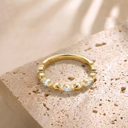 Schmaler Damenring aus 14 Karat vergoldetem Silber mit rundum verlaufenden Zirkoniasteinen auf beigem Naturstein.