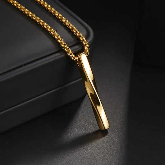  Nahaufnahme einer goldfarbenen Edelstahl-Kette mit einem glänzenden, verdrehten Stab-Anhänger (Bar-Anhänger) auf einem dunklen Hintergrund, der den Glanz hervorhebt.