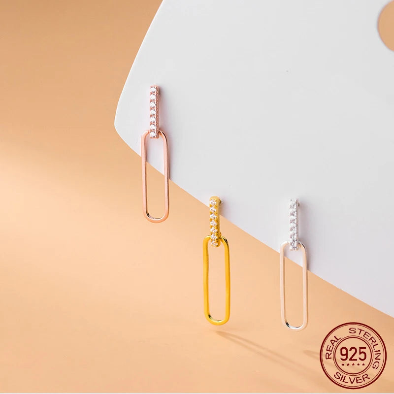Nahaufnahme der geometrischen 925er Silber-Ohrstecker mit Zirkonia-Besatz und ovalem Anhänger in Roségold, Gelbgold und Silber.