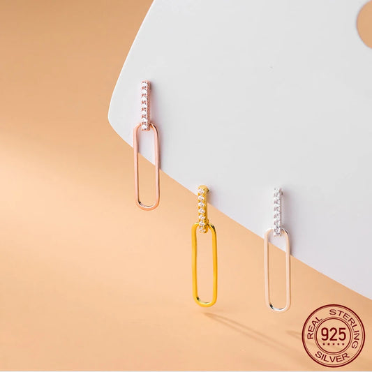 Nahaufnahme der geometrischen 925er Silber-Ohrstecker mit Zirkonia-Besatz und ovalem Anhänger in Roségold, Gelbgold und Silber.