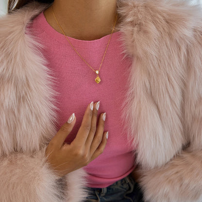 Frau in rosa Shirt und kuscheliger Kunstfelljacke trägt eine zarte, 18K vergoldete Halskette aus Edelstahl mit Herz-Anhänger.