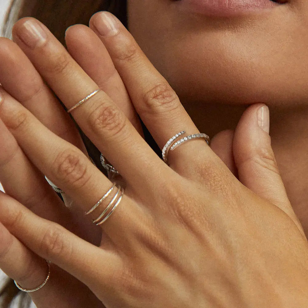 „Drei verschiedene offene Ringe aus Silber und Gold an einer Hand getragen, kombiniert im trendigen Stacking-Look.“