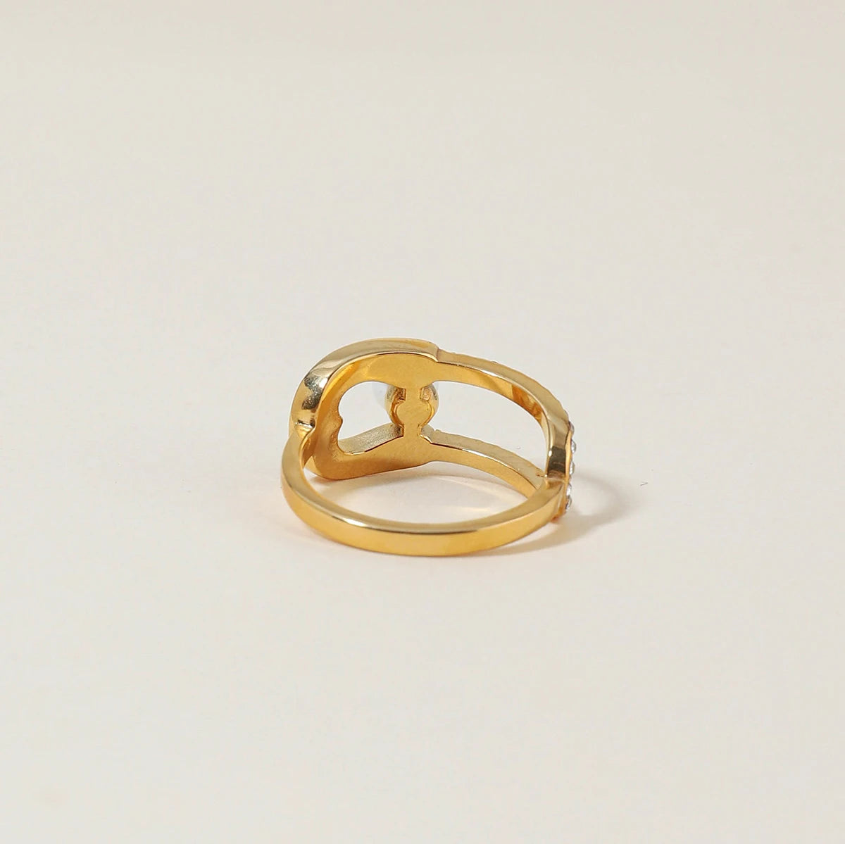 goldfarbener Ring aus Edelstahl, 18K PVD-vergoldet, mit Strasssteinen und einer Perle, freigestellt auf einem weißen Hintergrund.