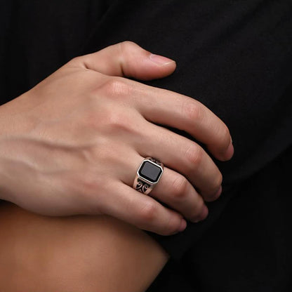 Hand hält massiven Siegelring aus Silber mit schwarzem Stein und seitlicher Gravur