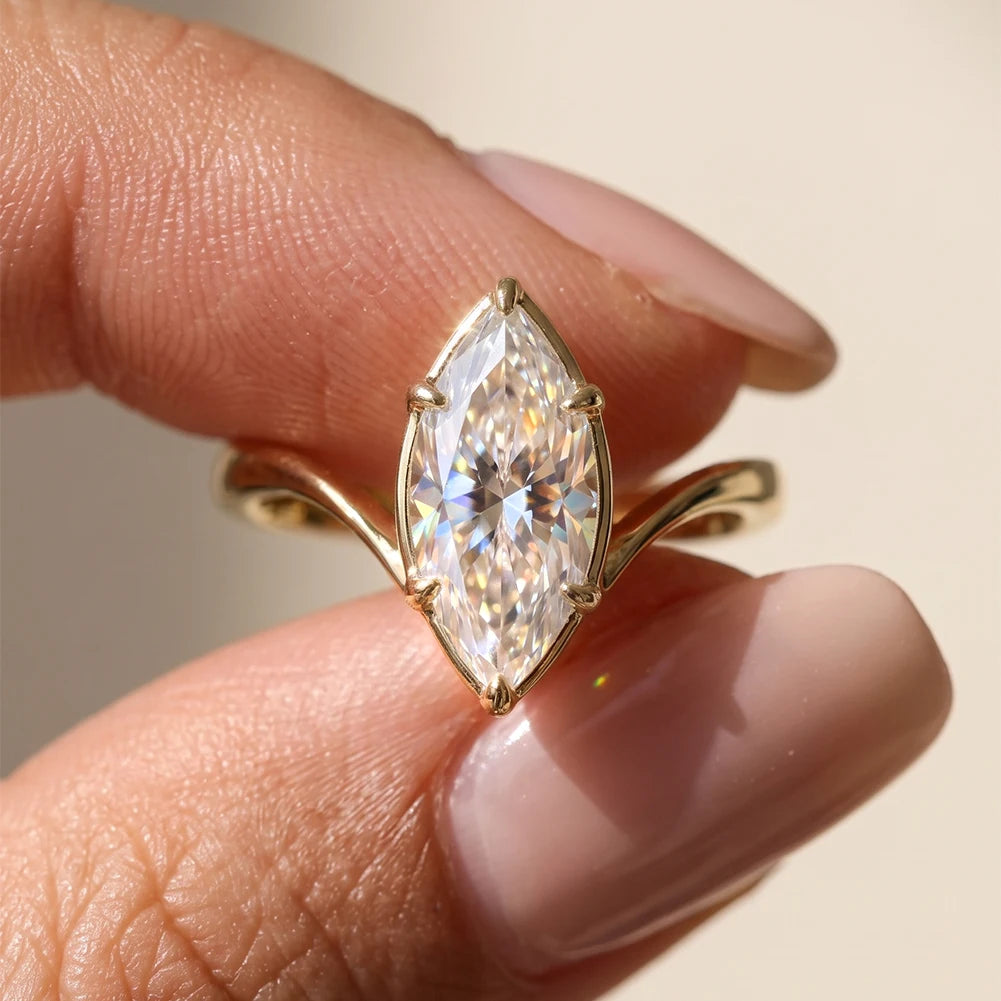 Nahaufnahme beim Halten des goldenen Verlobungsrings mit auffälligem Marquise-Zirkonia