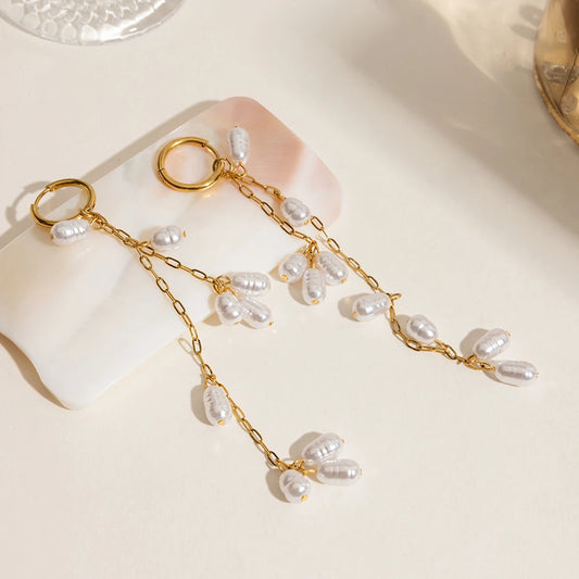 Ein Paar lange Ohrhänger aus 18K vergoldetem Edelstahl mit Acrylperlen, flach auf einer Oberfläche liegend.