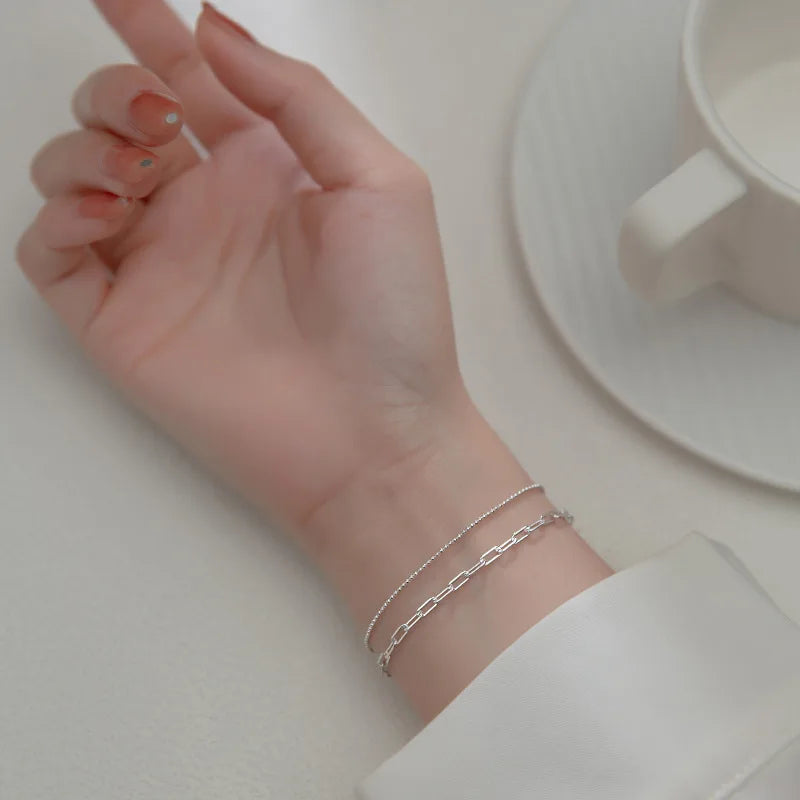 Elegantes Tragebild am Handgelenk: Zweireihiges platinierte Silberarmband kombiniert mit einer weißen Bluse