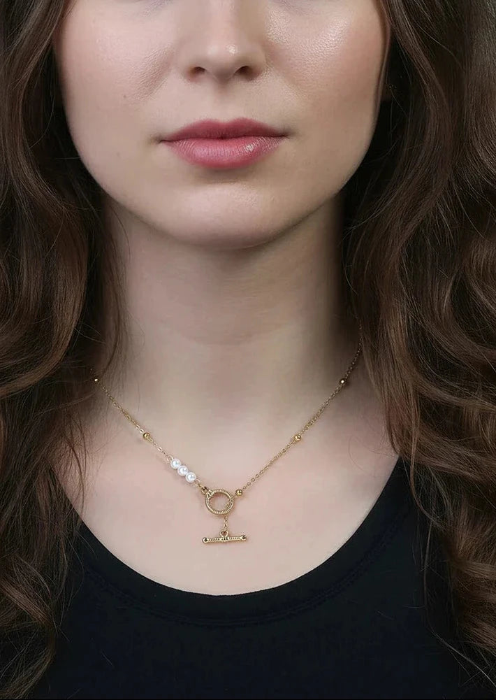 Eine Frau trägt die vergoldete Edelstahl-Kette mit Knebelverschluss und Muschelperlen zum schwarzen Oberteil.