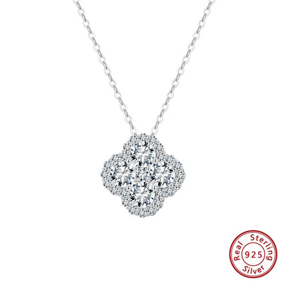 Nahaufnahme einer Silbernen Halskette mit Kleeblatt-Anhänger und passenden Ohrsteckern, gefertigt aus  925er Silber und Zirkonia, präsentiert auf blauem Untergrund.