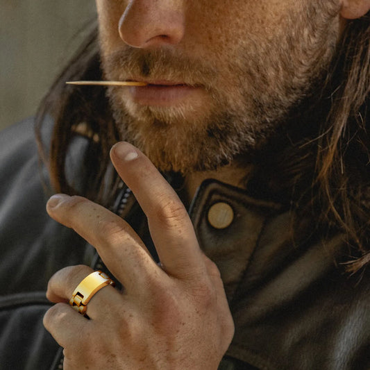 Ein Mann mit Bart trägt einen goldfarbenen Edelstahl-Gliederring am Finger, präsentiert in einer Nahaufnahme.