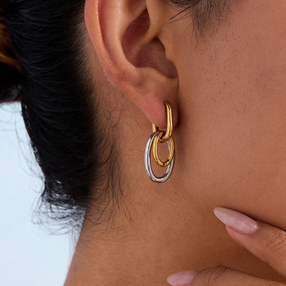 Statement-Ohrhänger in Gold und Silber am Ohr einer Frau getragen | ovale Ohrringe aus vergoldetem Edelstahl