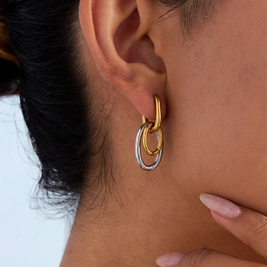 Statement-Ohrhänger in Gold und Silber am Ohr einer Frau getragen | ovale Ohrringe aus vergoldetem Edelstahl