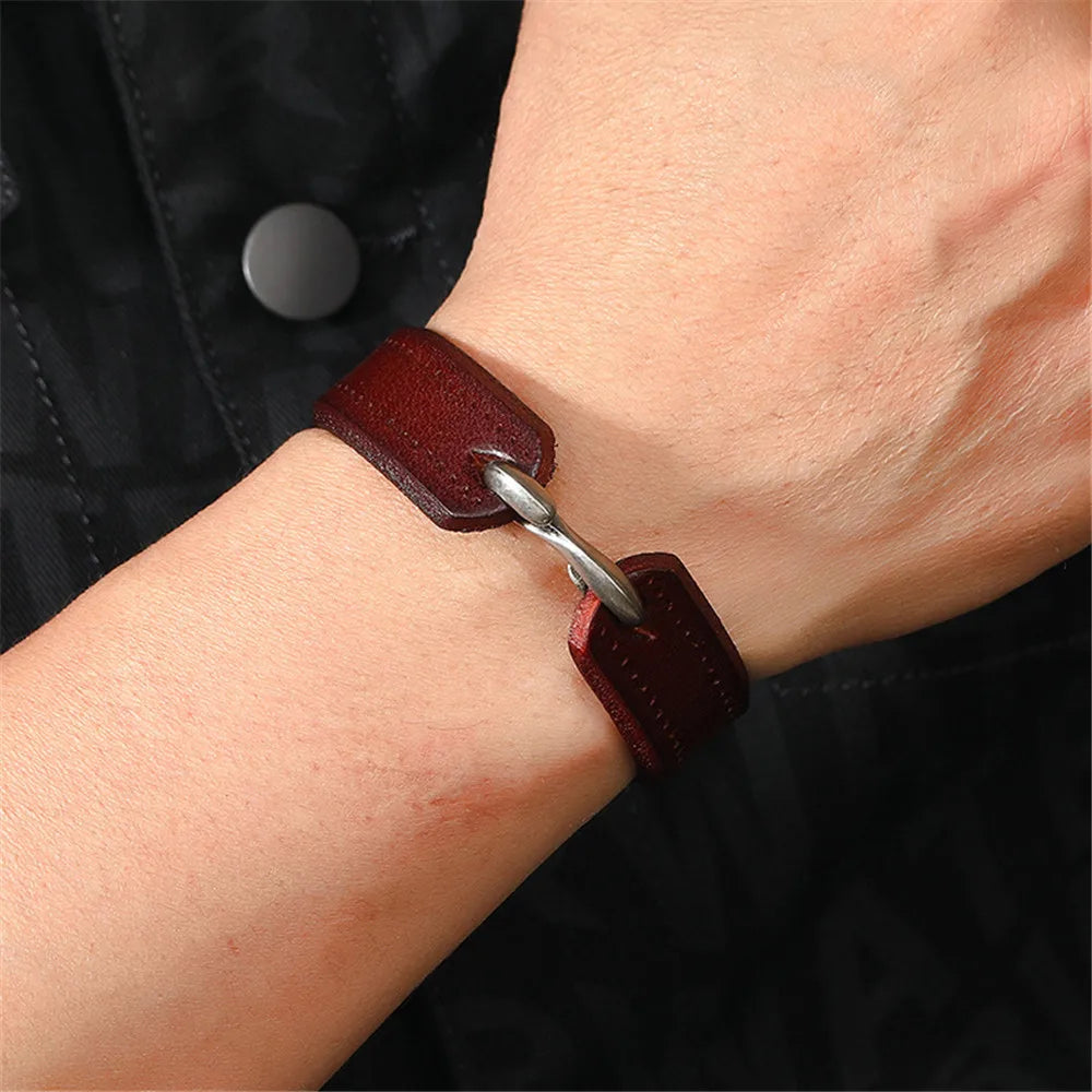 Nahaufnahme am Handgelenk: Ein Mann trägt das dunkelbraune, breite Echtleder-Armband mit dem silbernen Metallhaken nach oben gedreht.