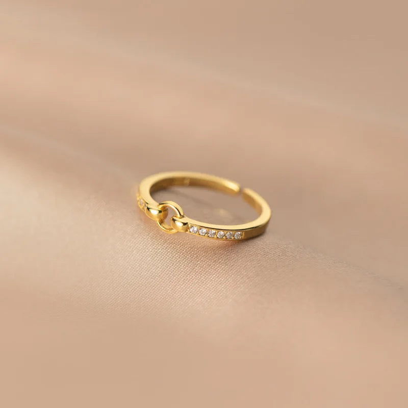 Eleganter, vergoldeter Sterling Silber Ring mit einer Reihe kleiner Zirkonia-Steine, präsentiert auf glänzendem, sandfarbenem Seidenstoff.