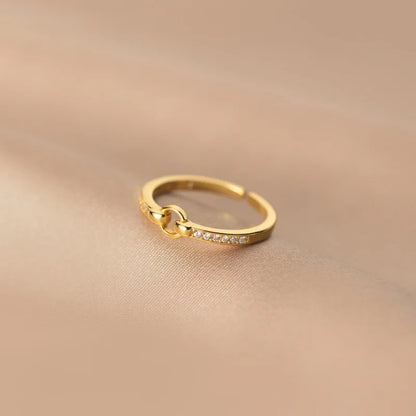 Eleganter, vergoldeter Sterling Silber Ring mit einer Reihe kleiner Zirkonia-Steine, präsentiert auf glänzendem, sandfarbenem Seidenstoff.