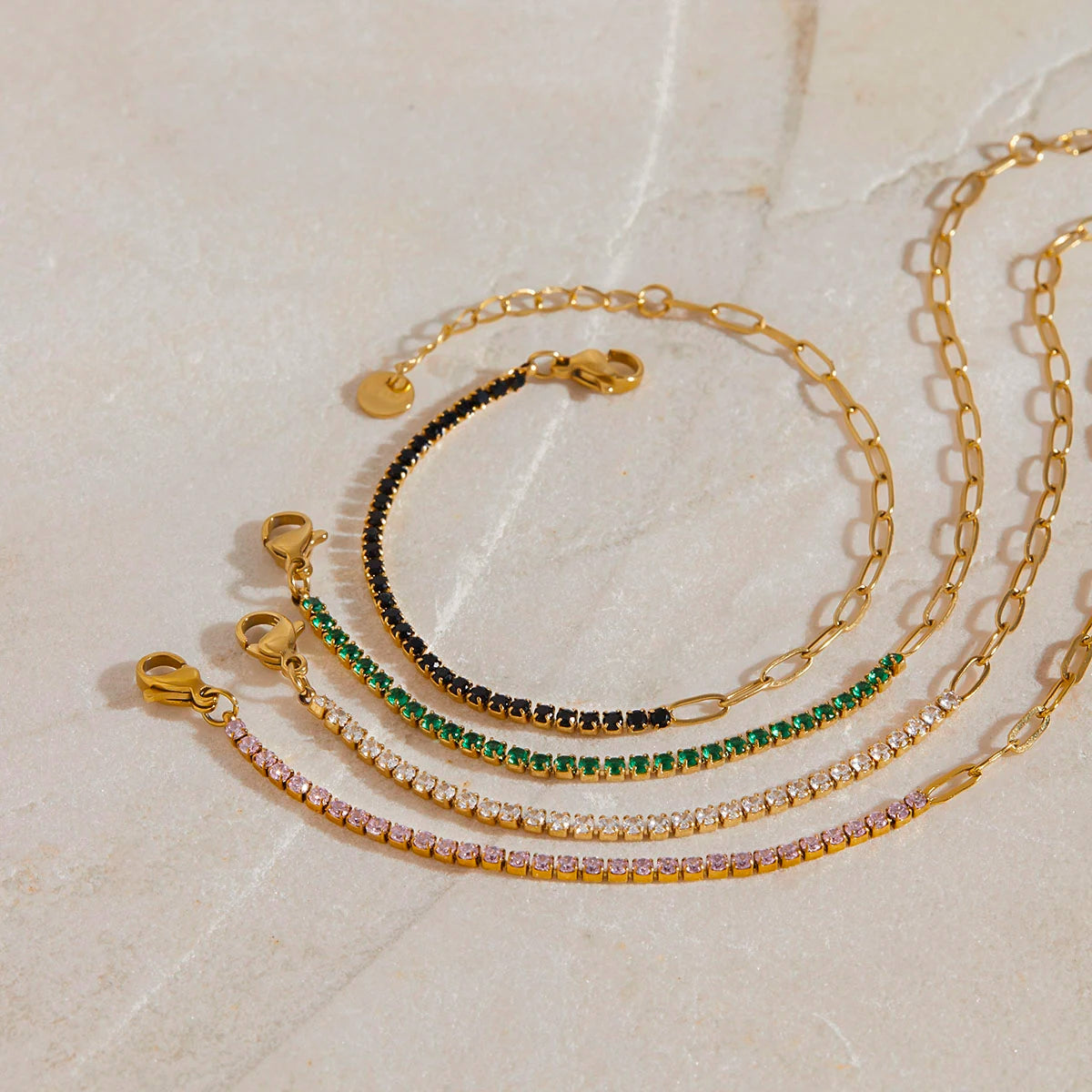 „Drei goldvergoldete Edelstahl-Armbänder dekorativ auf hellem Naturstein arrangiert – perfekt für einen eleganten, wasserfesten Alltags-Look.“