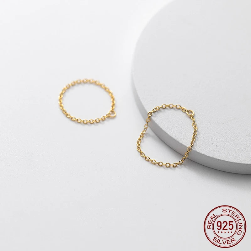 Nahaufnahme von zwei filigranen Gliederketten-Ringen aus 925er Sterling Silber mit 18K Goldplattierung auf weißem Podest.