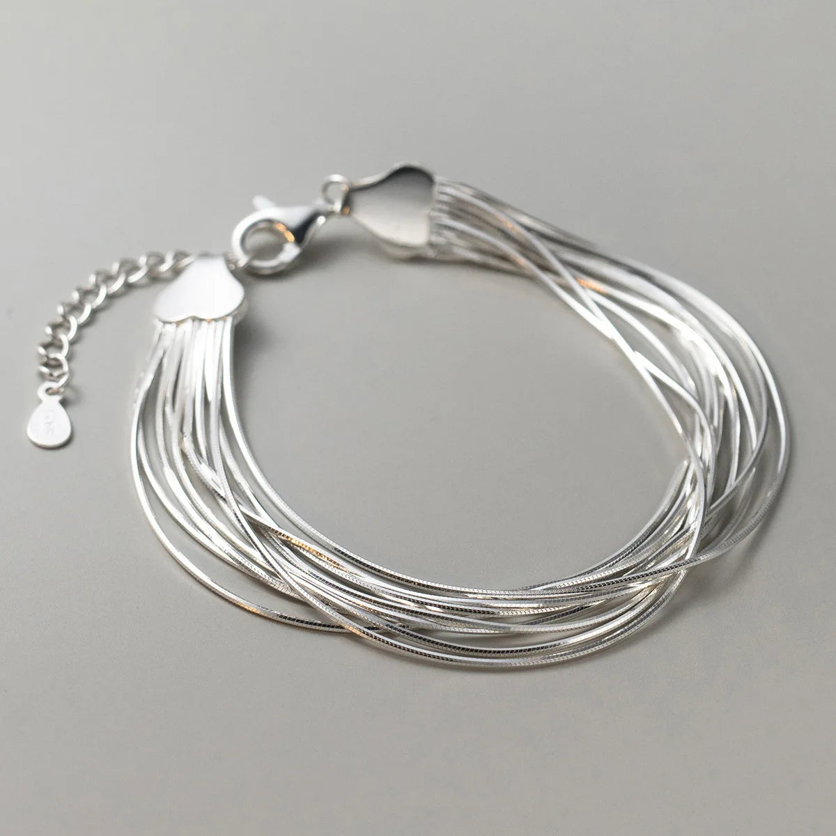 Gesamtansicht des mehrreihigen Schlangenketten-Armbands aus 925 Sterling Silber auf grauem Hintergrund