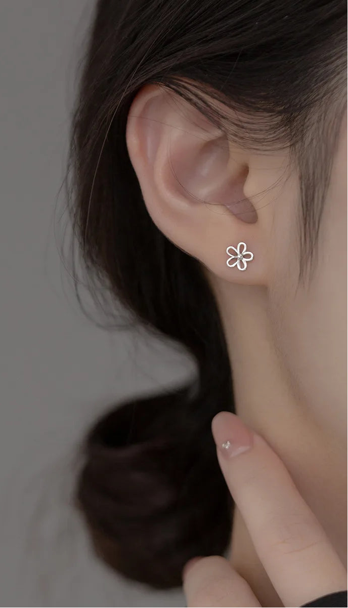 Model präsentiert den kleinen, silbernen Blumen-Ohrstecker dezent am Ohrläppchen.