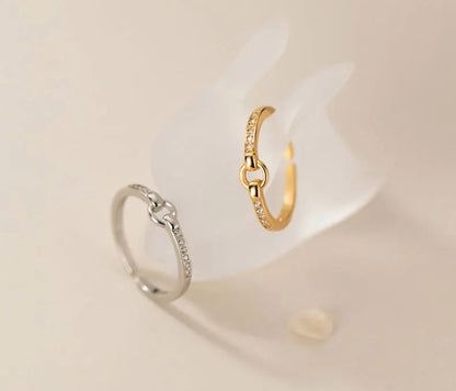 Der filigrane Zirkonia-Ring in zwei Ausführungen: Einmal in reinem 925er Silber und einmal mit 18K Gelbgold-Vergoldung, elegant auf einem weißen Halter arrangiert.