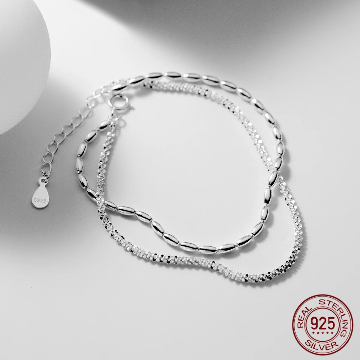 Zweireihiges Damen-Armband aus 925 Sterling Silber mit ovalen Reiskorn-Gliedern und einer funkeld geschliffenen Kordelkette auf hellem Untergrund