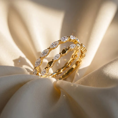Zwei feine vergoldete Vorsteckringe mit Marquise-Zirkoniasteinen im Stacking-Look auf sanft drpapiertem, hellem Stoff.