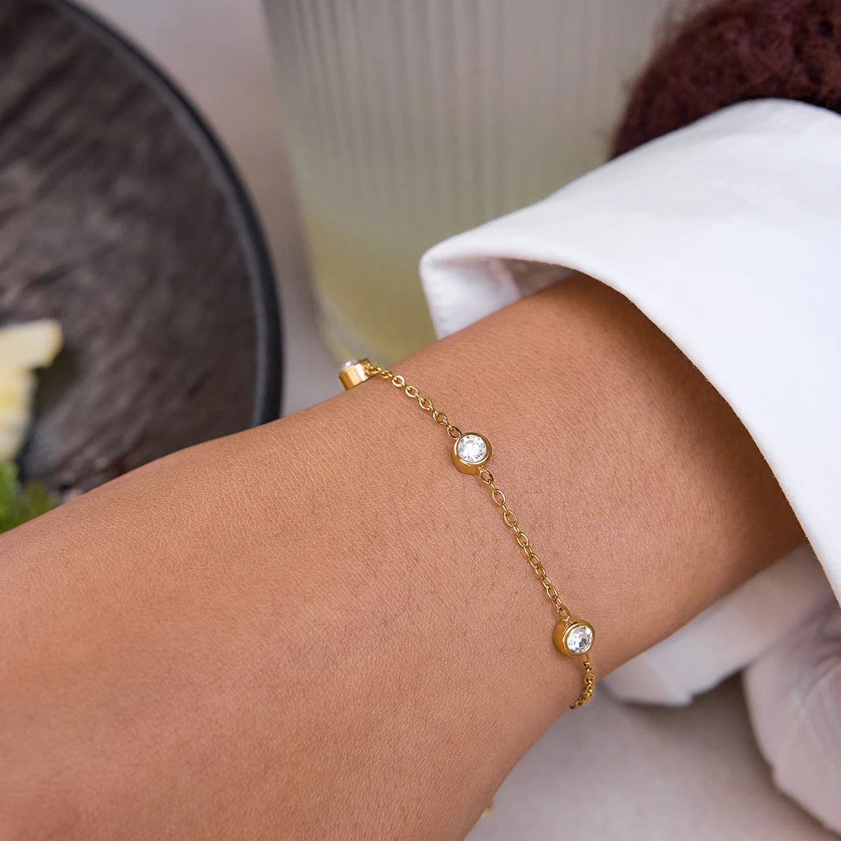 Nahaufnahme des filigranen, 18K vergoldeten Edelstahl-Gliederarmbands mit drei runden, eingefassten Zirkonia-Steinen am Handgelenk.
