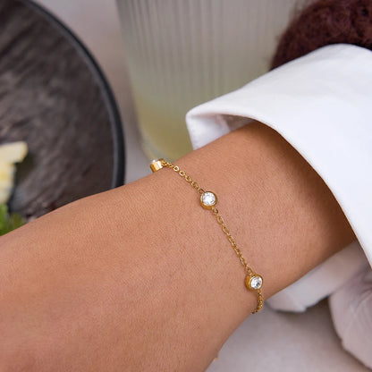 Nahaufnahme des filigranen, 18K vergoldeten Edelstahl-Gliederarmbands mit drei runden, eingefassten Zirkonia-Steinen am Handgelenk.