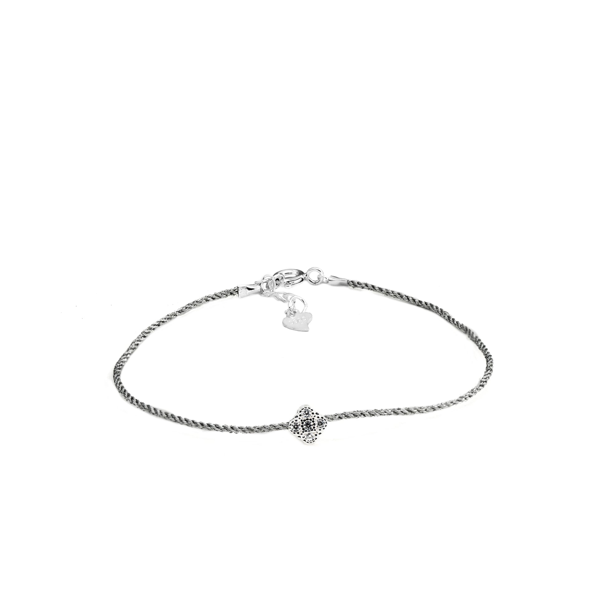 Draufsicht auf ein filigranes Armband mit Kettendesign aus 925er Silber, einem kleinen runden Anhänger mit Zirkoniastein in der Mitte und einem Verschluss mit einem kleinen Herz-Detail.