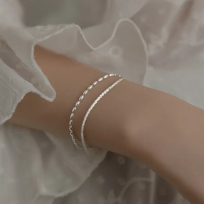 Filigraner Stacking-Look: Zweireihiges Echtsilber-Armband zart am Handgelenk zu einem romantischen Blusenärmel getragen